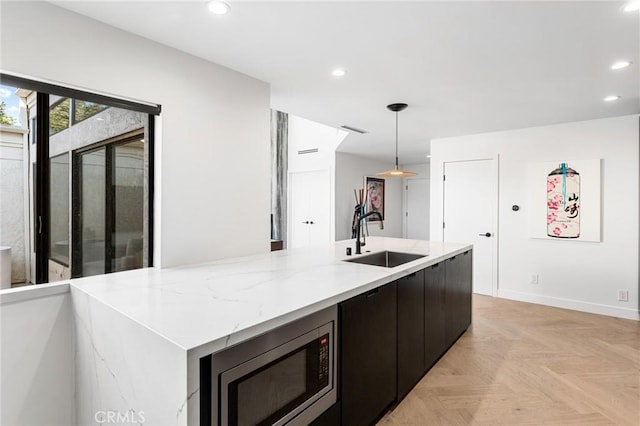 45 Morena, Irvine, CA 92612 - kitchen with stainless steel microwave, recessed lighting, hanging light fixtures, a center island with sink, and light stone countertops