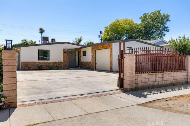 6535 Mary Ellen Ave, Valley Glen, CA 91401 - view of front facade featuring an attached garage, a fenced front yard, driveway, stucco siding, and stone siding