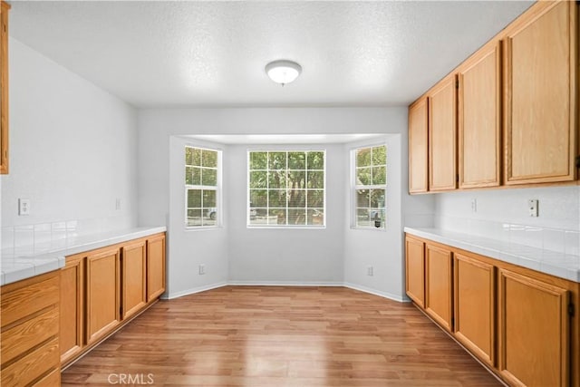 43733 6th St E, Lancaster, CA 93535 - kitchen with tile countertops, light wood finished floors, and a textured ceiling