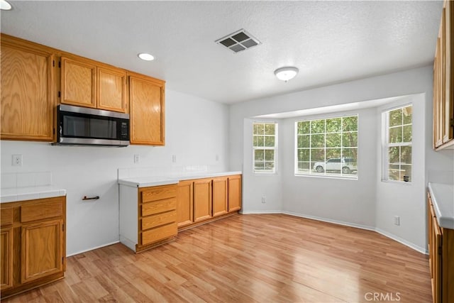 43733 6th St E, Lancaster, CA 93535 - kitchen featuring stainless steel microwave, light wood finished floors, light countertops, brown cabinetry, and recessed lighting