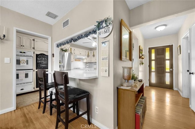 15902 Santa Fe St, Whittier, CA 90603 - kitchen with double oven, light wood-style flooring, a kitchen breakfast bar, under cabinet range hood, and a peninsula