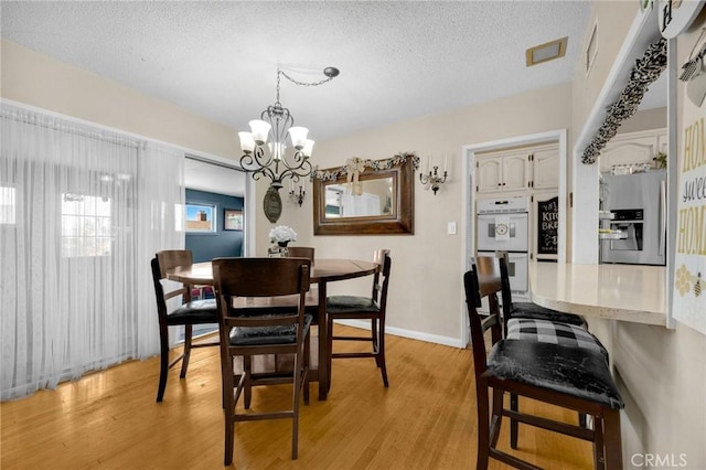 15902 Santa Fe St, Whittier, CA 90603 - dining space with light wood-style floors, a chandelier, and a textured ceiling