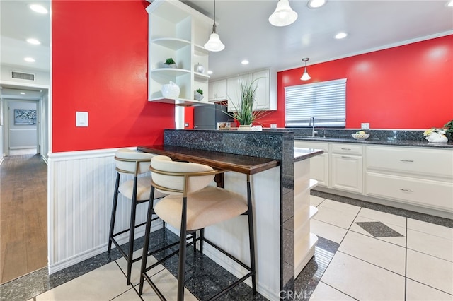 19615 E Tudor St, Covina, CA 91724 - kitchen with a wainscoted wall, white cabinets, a breakfast bar area, hanging light fixtures, and light tile patterned flooring