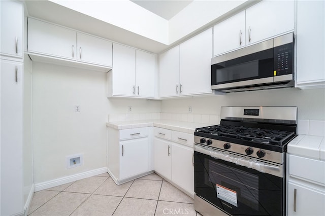 11500 Winery Dr, Fontana, CA 92337 - kitchen featuring stainless steel appliances, tile countertops, white cabinetry, and light tile patterned floors