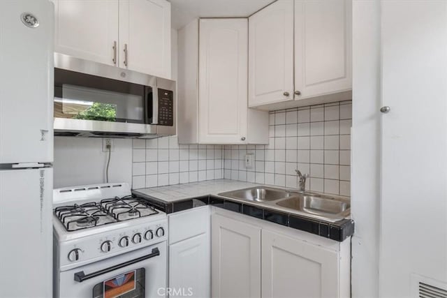 18713 Vanowen St, Reseda, CA 91335 - kitchen with white appliances, tile countertops, white cabinets, and tasteful backsplash