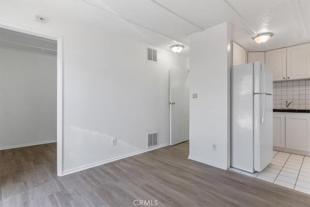 18713 Vanowen St, Reseda, CA 91335 - kitchen with freestanding refrigerator, light wood-style floors, white cabinets, and backsplash