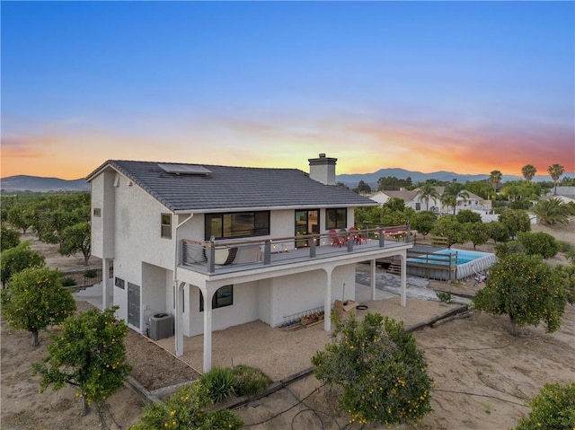 33851 Madera De Playa, Temecula, CA 92592 - rear view of house with roof mounted solar panels, a balcony, a patio, stucco siding, and a chimney