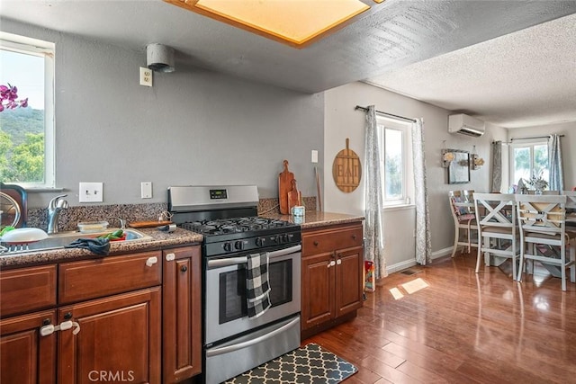 1996 Rainbow Glen Rd, Fallbrook, CA 92028 - kitchen featuring stainless steel gas range oven, an AC wall unit, brown cabinets, dark wood finished floors, and a textured ceiling