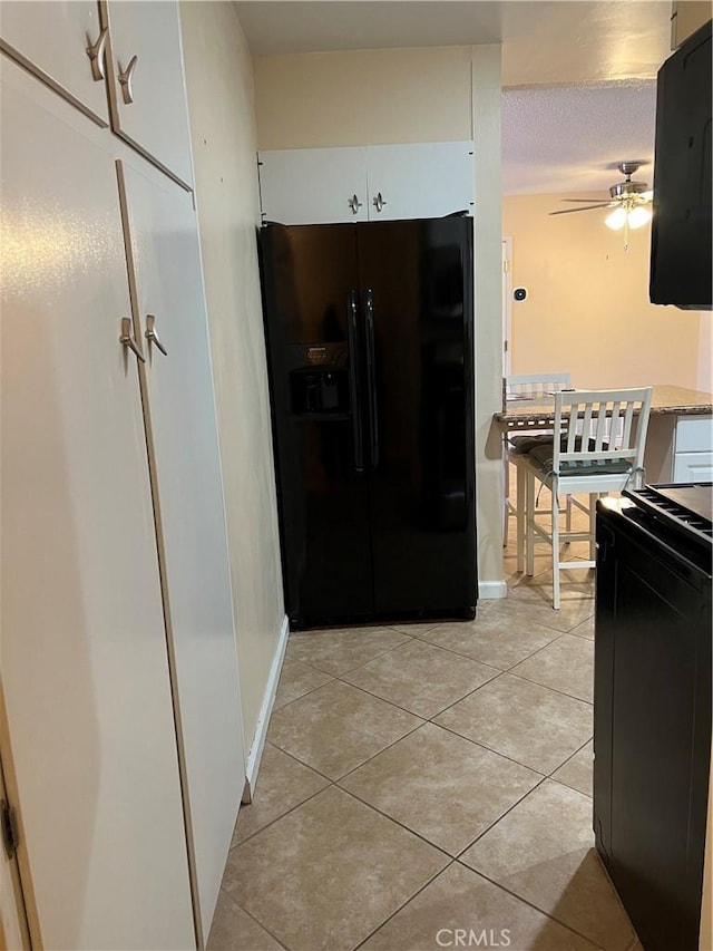 1441 Edgewood Ln, Hemet, CA 92543 - kitchen with black appliances, a ceiling fan, light tile patterned floors, white cabinets, and extractor fan