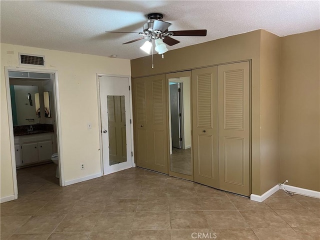 1441 Edgewood Ln, Hemet, CA 92543 - unfurnished bedroom featuring a closet, a textured ceiling, light tile patterned floors, ensuite bath, and ceiling fan