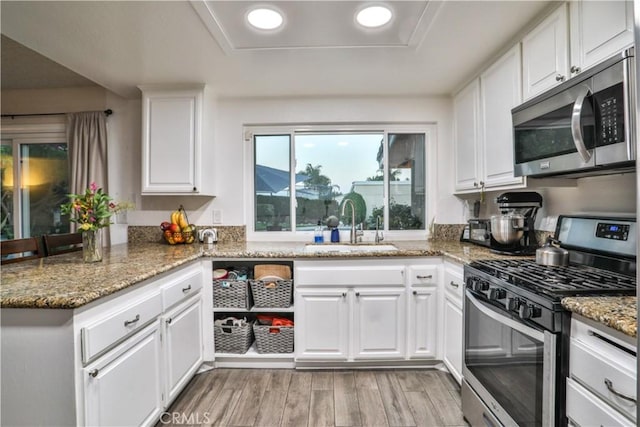 6073 Cameo St, Rancho Cucamonga, CA 91701 - kitchen featuring appliances with stainless steel finishes, a peninsula, white cabinetry, light wood-style flooring, and light stone counters
