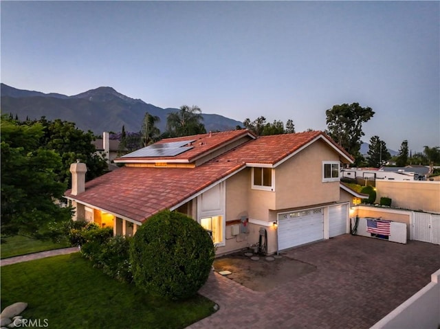 6073 Cameo St, Rancho Cucamonga, CA 91701 - view of front of home with roof mounted solar panels, a garage, decorative driveway, stucco siding, and a mountain view