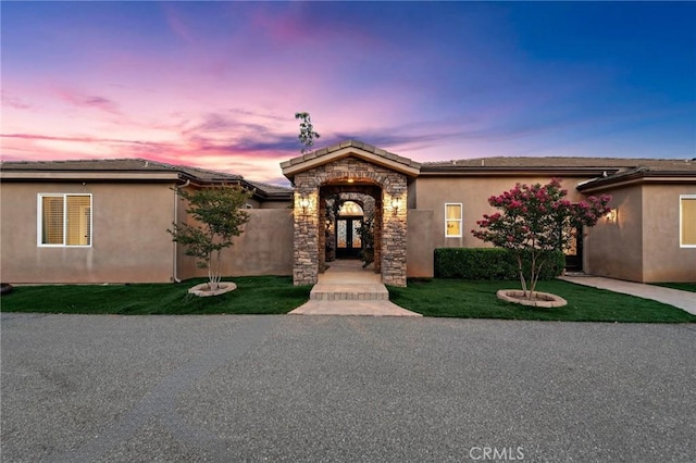 38150 Via Huerta, Murrieta, CA 92562 - view of front of home with stucco siding, stone siding, a lawn, and french doors