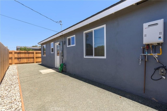 715 N 3rd St, Lompoc, CA 93436 - view of side of home featuring water heater, a fenced backyard, stucco siding, and a patio area