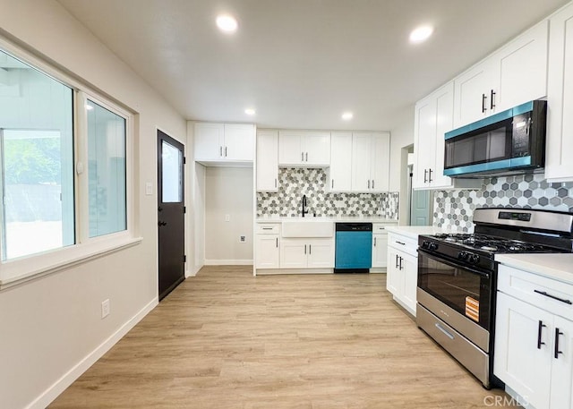 6692 Elm Ave, San Bernardino, CA 92404 - kitchen with stainless steel appliances, decorative backsplash, white cabinets, light countertops, and light wood-style floors