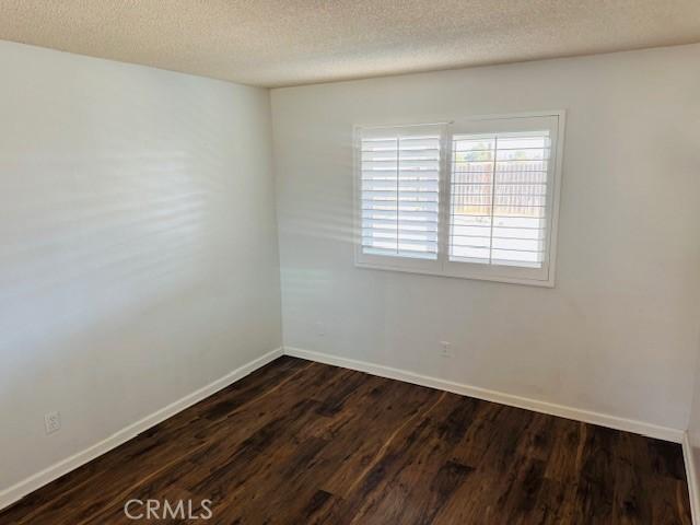 98 Lori Way, Banning, CA 92220 - empty room featuring dark wood-type flooring and a textured ceiling