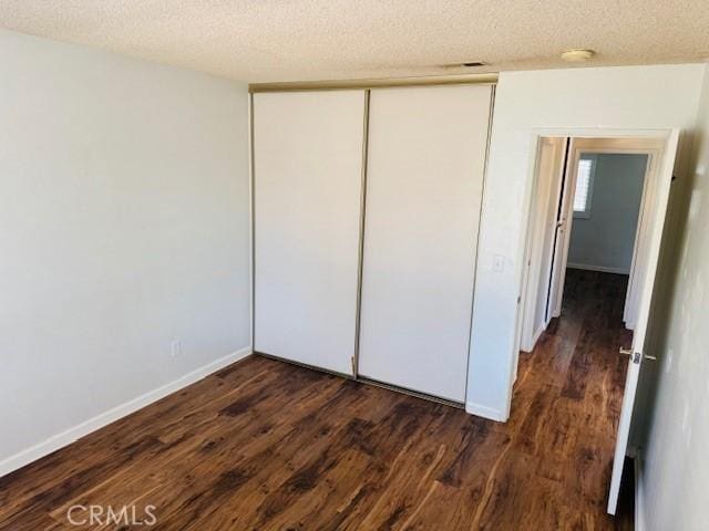 98 Lori Way, Banning, CA 92220 - unfurnished bedroom featuring dark wood-type flooring, a textured ceiling, and a closet