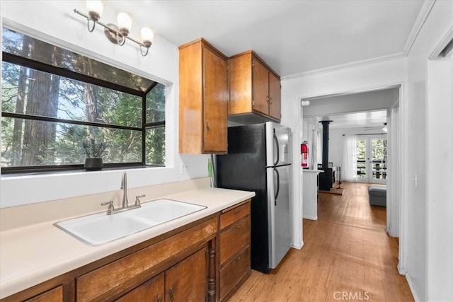 23717 Scenic Dr, Crestline, CA 92325 - kitchen featuring freestanding refrigerator, brown cabinetry, a wood stove, light countertops, and light wood finished floors