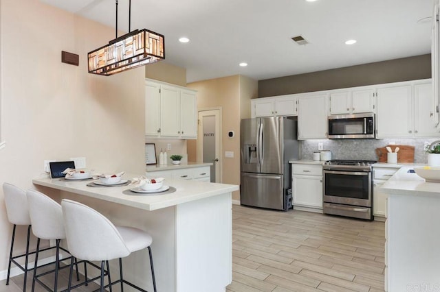 339 Alamo Way, Oceanside, CA 92057 - kitchen with appliances with stainless steel finishes, a peninsula, backsplash, light countertops, and light wood-style floors
