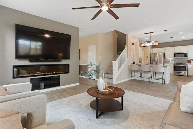339 Alamo Way, Oceanside, CA 92057 - living room with light wood-style floors, a ceiling fan, a glass covered fireplace, stairs, and recessed lighting