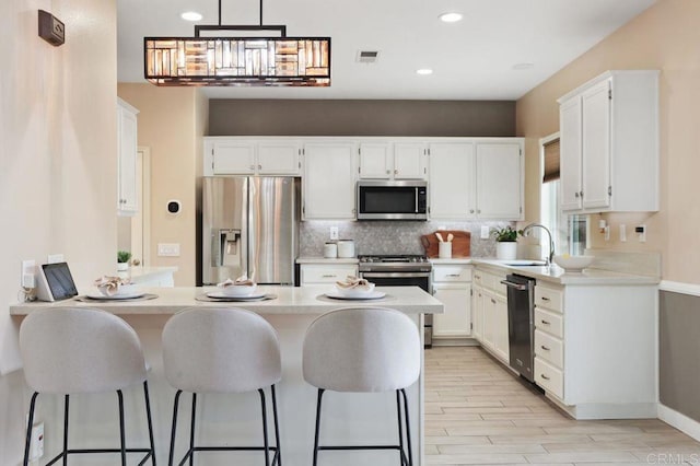 339 Alamo Way, Oceanside, CA 92057 - kitchen with appliances with stainless steel finishes, a peninsula, light countertops, tasteful backsplash, and light wood-style flooring
