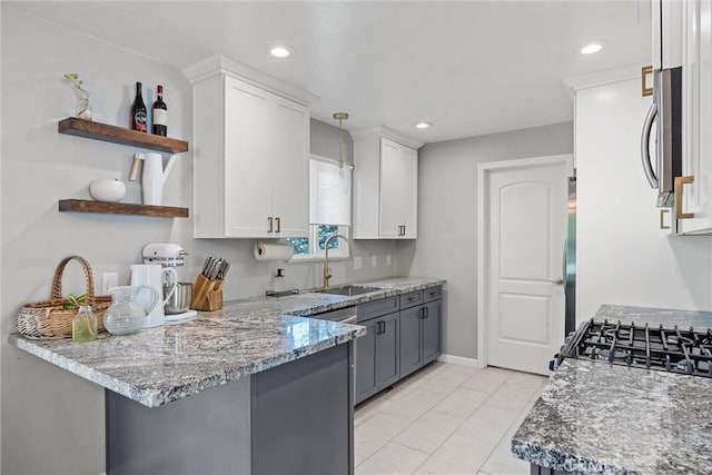 18 El Cerrito Dr, Chico, CA 95973 - kitchen with stainless steel microwave, open shelves, white cabinetry, a peninsula, and pendant lighting