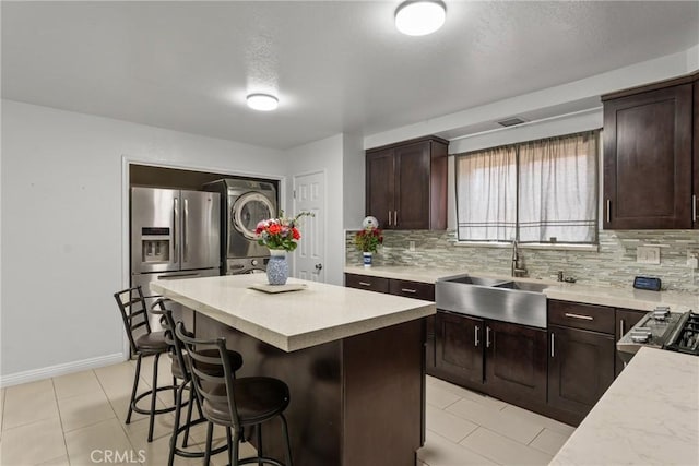 5983 Jones Ave, Riverside, CA 92505 - kitchen featuring estacked washer and dryer, stainless steel fridge, decorative backsplash, and a kitchen breakfast bar