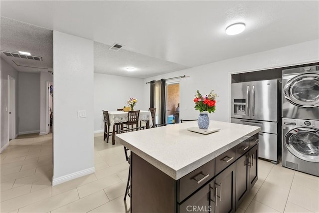 5983 Jones Ave, Riverside, CA 92505 - kitchen featuring stainless steel fridge with ice dispenser, stacked washer / dryer, light tile patterned floors, and a kitchen island