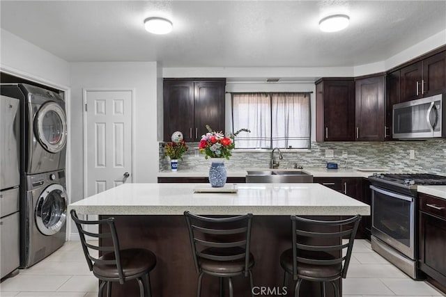 5983 Jones Ave, Riverside, CA 92505 - kitchen featuring stainless steel appliances, stacked washer / drying machine, light tile patterned flooring, and a breakfast bar area