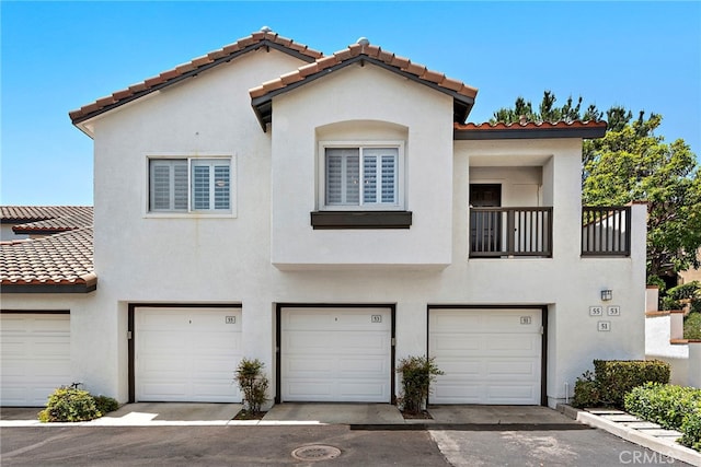 55 Rabano Unit 240, Rancho Santa Margarita, CA 92688 - view of front facade with a garage, a tiled roof, stucco siding, and a balcony