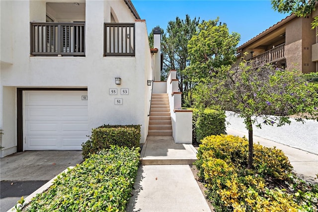 55 Rabano Unit 240, Rancho Santa Margarita, CA 92688 - view of front of home with stucco siding, a garage, stairs, and a chimney