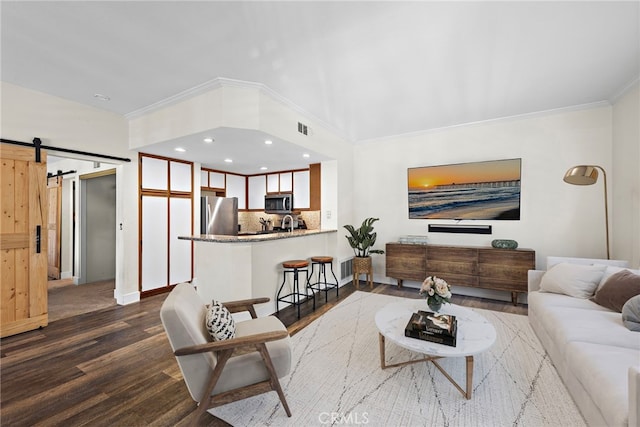 55 Rabano Unit 240, Rancho Santa Margarita, CA 92688 - living area featuring a barn door, ornamental molding, dark wood finished floors, and recessed lighting