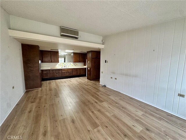 13620 Alderwood Ln Unit 76D, Seal Beach, CA 90740 - unfurnished living room with light wood-style flooring, a wall mounted air conditioner, and a textured ceiling