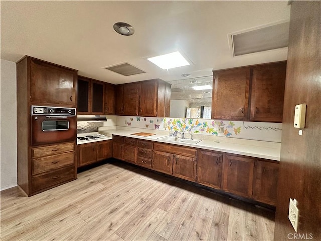 13620 Alderwood Ln Unit 76D, Seal Beach, CA 90740 - kitchen featuring wall oven, light wood-style floors, tasteful backsplash, and light countertops
