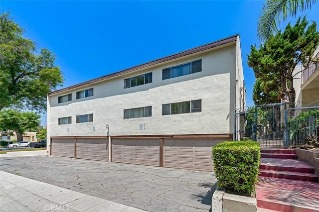 820 N Raymond Ave, Pasadena, CA 91103 - rear view of house with stucco siding, an attached garage, and asphalt driveway