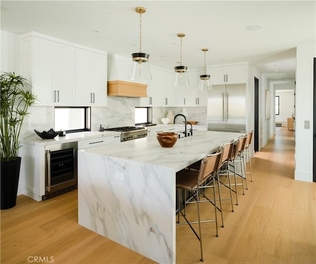 1313 Ocean Ave, Seal Beach, CA 90740 - kitchen with wine cooler, custom exhaust hood, light wood-style floors, and decorative backsplash