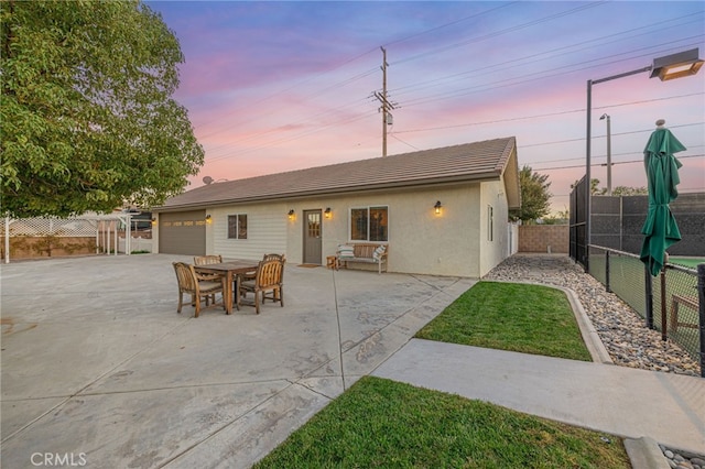2534 Desert Rose Dr, Lancaster, CA 93536 - back of house at dusk featuring a fenced backyard, stucco siding, driveway, a garage, and a tile roof