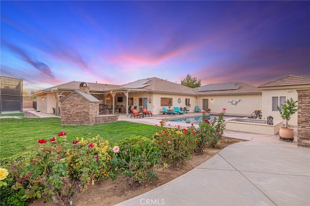 2534 Desert Rose Dr, Lancaster, CA 93536 - back of house at dusk with a patio area, roof mounted solar panels, a yard, and stucco siding