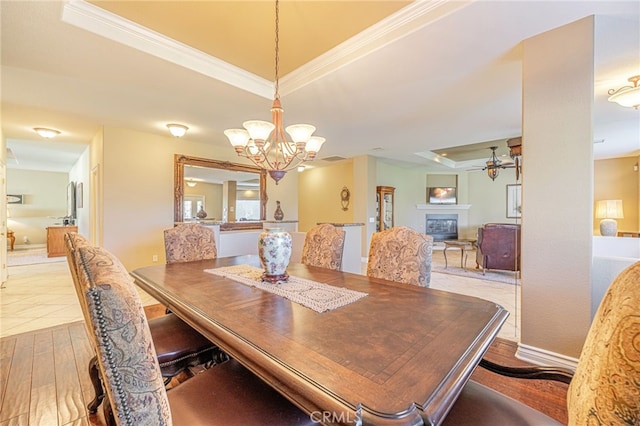 2534 Desert Rose Dr, Lancaster, CA 93536 - dining space with a raised ceiling, a chandelier, a glass covered fireplace, ornamental molding, and wood finished floors
