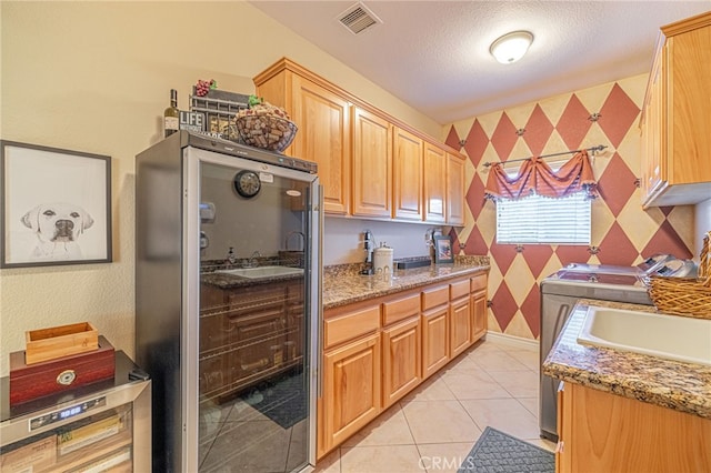 2534 Desert Rose Dr, Lancaster, CA 93536 - kitchen featuring fridge, wallpapered walls, light stone countertops, independent washer and dryer, and a textured ceiling