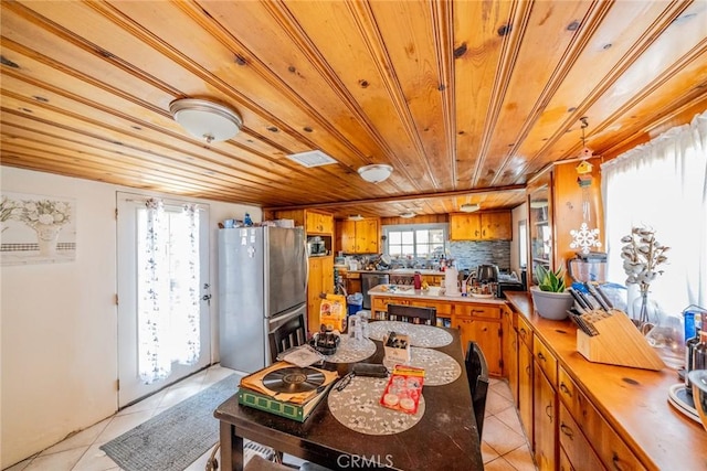 9964 Cedar Ave, Bloomington, CA 92316 - kitchen with stainless steel appliances, wood ceiling, brown cabinetry, and light tile patterned floors