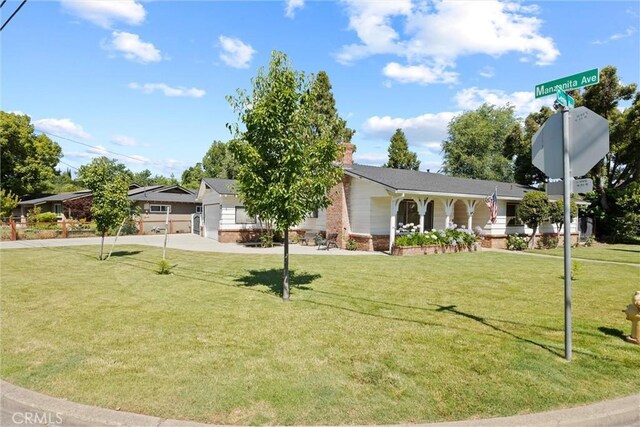1094 Manzanita Ave, Chico, CA 95926 - view of front of home featuring brick siding, a front lawn, driveway, and a chimney