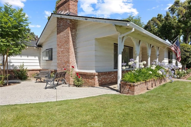 1094 Manzanita Ave, Chico, CA 95926 - view of property exterior with a chimney, a lawn, a patio, brick siding, and covered porch