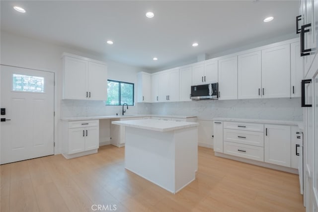 7734 N Glenoaks Blvd, Burbank, CA 91504 - kitchen with stainless steel microwave, backsplash, light wood-style floors, white cabinets, and recessed lighting