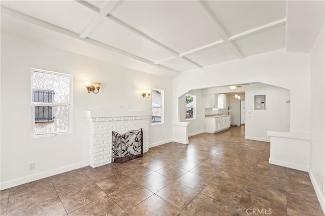 8727 S Harvard Blvd, Los Angeles, CA 90047 - unfurnished living room featuring coffered ceiling, beamed ceiling, arched walkways, a fireplace, and tile patterned floors