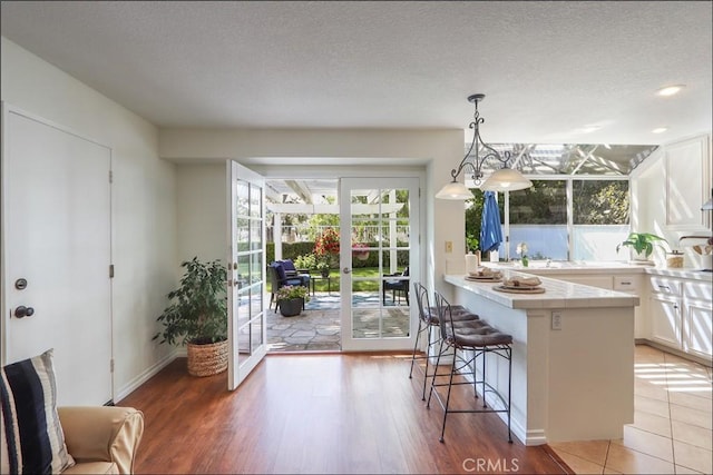 3 Blue Heron Ln, Aliso Viejo, CA 92656 - kitchen with white cabinetry, a kitchen breakfast bar, a peninsula, light countertops, and pendant lighting