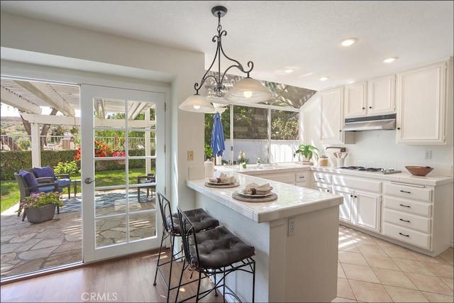 3 Blue Heron Ln, Aliso Viejo, CA 92656 - kitchen with tile counters, under cabinet range hood, white cabinets, healthy amount of natural light, and recessed lighting