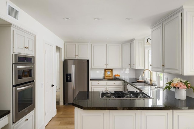 17274 Calle Mayor, Rancho Santa Fe, CA 92067 - kitchen with stainless steel appliances, light wood finished floors, a peninsula, backsplash, and recessed lighting