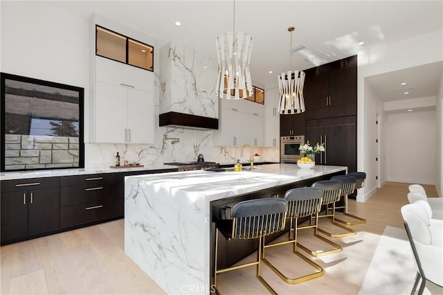 19031 Fowler Ave, North Tustin, CA 92705 - kitchen with backsplash, a kitchen breakfast bar, a large island with sink, hanging light fixtures, and recessed lighting