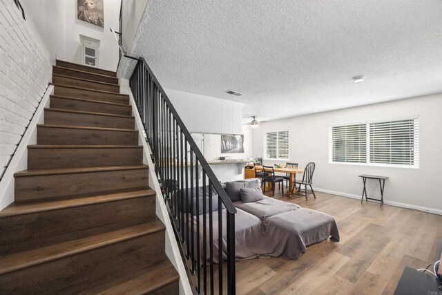 9847 Mission Vega Rd Unit 3, Santee, CA 92071 - stairs featuring wood finished floors, a textured ceiling, and ceiling fan
